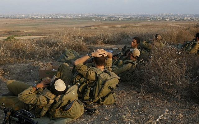 Israeli soldiers rest in southern Israel along the border with Gaza (background), August 06, 2014. (Photo credit: Miriam Alster/Flash90)