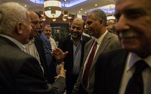 Hamas deputy leader Moussa Abu Marzouk (center) shakes hands with the head of the Palestinian delegation Azzam al-Ahmad (left) upon their arrival at a Cairo hotel after a meeting with senior Egyptian intelligence officials, August 11, 2014. (photo credit: AFP/Khaled Desouki) 
