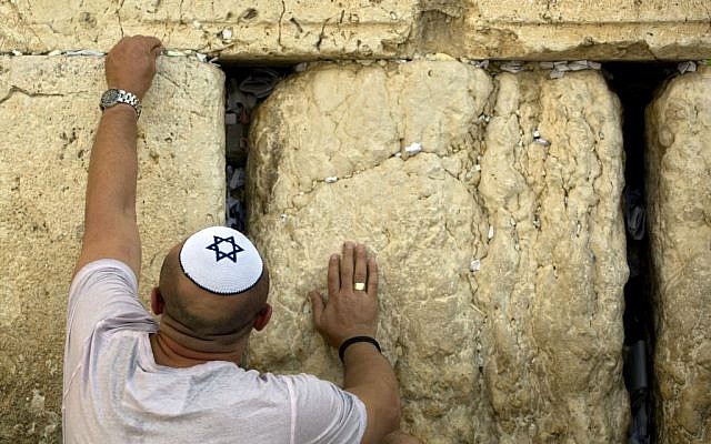 A Jewish man places a note at the Western Wall. (photo credit: AP/Sebastian Scheiner)