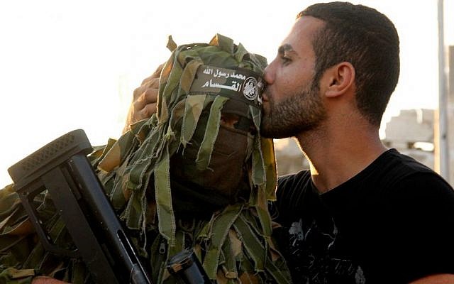 A Palestinian man kisses an Izz ad-Din Al-Qassam sniper over the debris of destroyed houses in Shejaiyah, neighborhood of Gaza City, in the northern Gaza Strip, August 27, 2014 [photo credit: Abed Rahim Khatib/Flash90]
