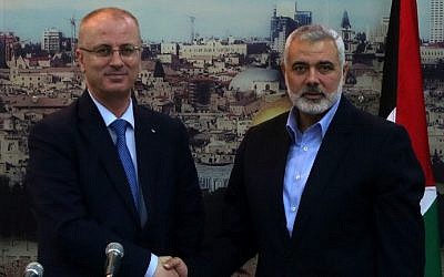 Hamas's former Gaza prime minister and leader, Ismail Haniyeh (right), shakes hands with Palestinian Authority Prime Minister Rami Hamdallah at Haniyeh's house in Gaza City, October 9, 2014. (photo credit: AFP/Said Khatib)