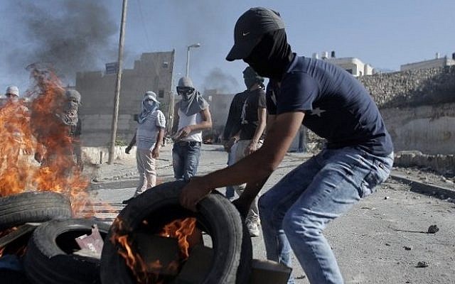 A Palestinian protester burns a tire during clashes with Israeli security officers in the Issawiya district of Arab East Jerusalem on October 24, 2014. (Photo credit: AFP / AHMAD GHARABLI)