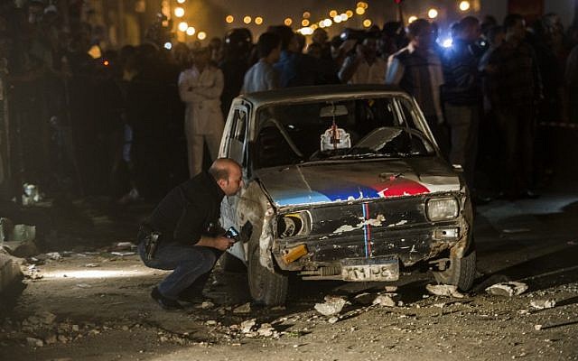 Egyptian police inspect a damaged car after a bomb exploded in Cairo late on October 14, 2014. (photo credit: AFP/KHALED DESOUKI)