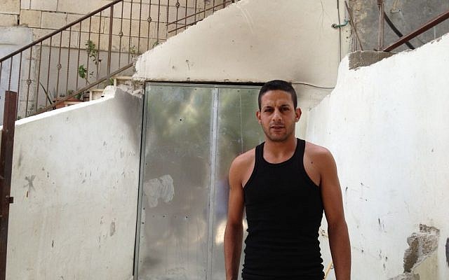 Anas Sarhan stands outside the temporary metal door of his former apartment in Silwan, now inhabited by Israeli security guards, October 2, 2014 (photo credit: Elhanan Miller/Times of Israel)