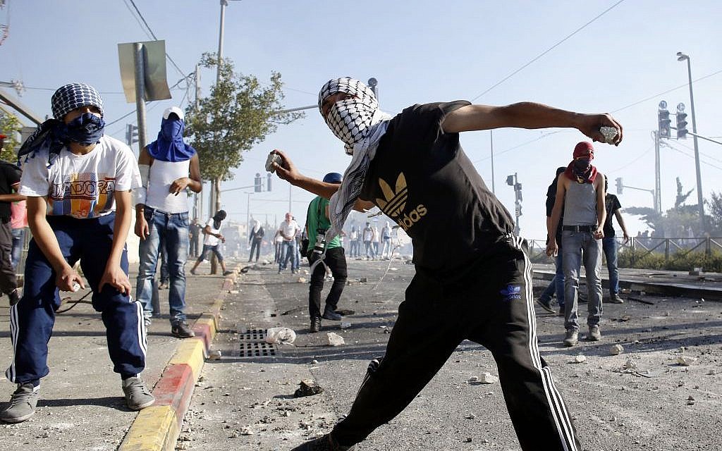 Masked Palestinian protesters throw stones at Israeli police during clashes in the Shuafat neighborhood in East Jerusalem, July 3, 2014 (photo credit: Sliman Khader/Flash90)
