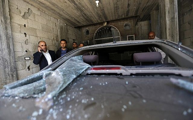 Fayez Abu Eitta, a Fatah leader in Gaza, speaks on the phone as he inspects the damage to his car in the parking lot of his home in Beit Lahiya, northern Gaza Strip on November 7, 2014. (Photo Credit: AFP/Mohammed Abed)