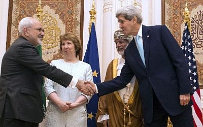 US Secretary of State John Kerry and Iranian Foreign Minister Javad Zarif  shake hands as Omani Minister Responsible for Foreign Affairs Yussef bin Alawi (2nd R) and former EU top diplomat Catherine Ashton watch in Muscat on November 9, 2014. (Photo credit: AFP PHOTO/NICHOLAS KAMM/POOL)