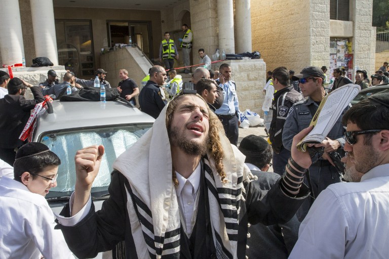 An ultra-Orthodox man prays at the scene of an attack in the Har Nof neighborhood in Jerusalem on November 18, 2014. (photo credit: AFP/ JACK GUEZ)