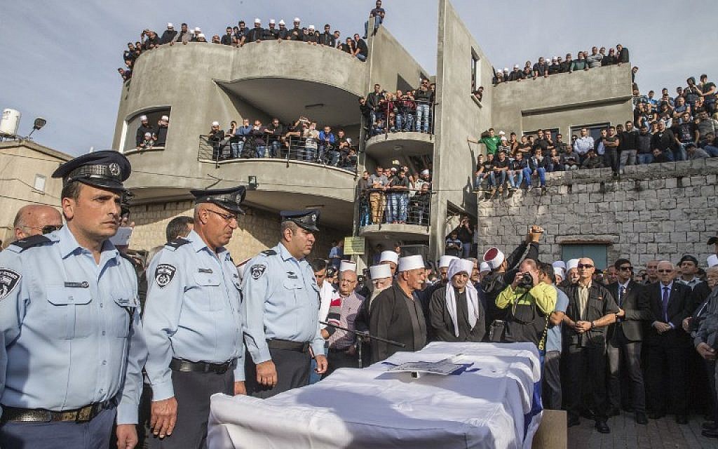 Police officers stand next to the coffin of Israeli police officer Zidan Saif, 30, a member of Israel's Druze minority, during his funeral in his northern home village of Yanuh-Jat, on November 19, 2014. Saif was killed during a terror attack on a Jerusalem synagogue the day before. (photo credit: AFP/Jack Guez)