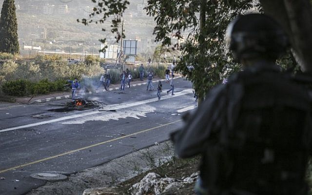 Rioters seen throwing rocks at Israeli border policemen at the entrance to the Arab village Kfar Kanna in northern Israel on November 8, 2014.  (photo credit: Hadas Parush/Flash90)