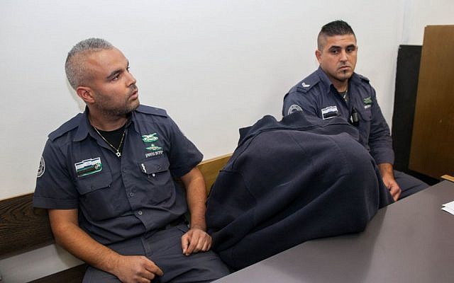 The Border Police officer, covered with shirt, accused of shooting to death a Palestinian teen on May 15 is brought to District Court in Jerusalem on November 23, 2014. (Photo credit: Yonatan Sindel/Flash90)