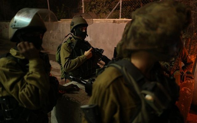 Israeli soldiers seen at the entrance to the Palestinian village of al-Aroub in the West Bank, where three Israeli soldiers were injured when a Palestinian driver rammed his car into them, close to the Gush Etzion Junction, November 5, 2014. (photo credit: Nati Shohat/Flash90)