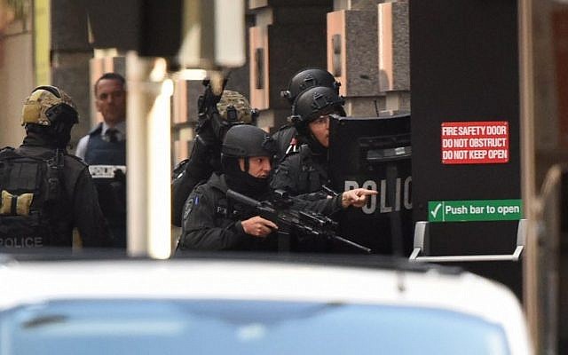 Police gesture as a hostage (unseen) escapes from an emergency exit during a hostage siege in the central business district of Sydney on December 15, 2014 (photo credit: AFP/William WestT)