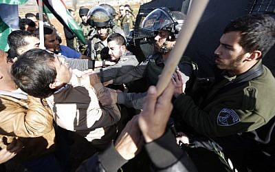 A border policeman grabs Palestinian official Ziad Abu Ein (L) during a demonstration in the West Bank on Wednesday, December 10, 2014 (photo credit: AFP/ABBAS MOMANI)