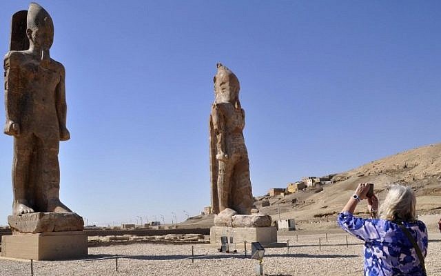 Illustrative: A tourist takes a picture of two colossal statues of Pharaoh Amenhotep III in Egypt's famed temple city of Luxor, December 14, 2014. (photo credit: AFP/Radwan Abu Elmagd)