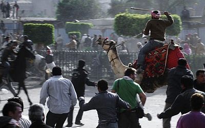 In this Wednesday, Februay 2, 2011 file photo, supporters of President Hosni Mubarak, riding camels and horses, fight with anti-Mubarak protesters in Cairo, Egypt. (Photo credit: AP/Mohammed Abu Zaid, File)