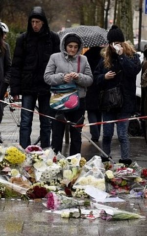 Floral tributes are laid on the ground during a minutes silence in Paris on January 8, 2015, a day after Islamist gunmen killed 12 people in an attack on the offices of satirical magazine  Charlie Hebdo. (photo credit: AFP/ MARTIN BUREAU