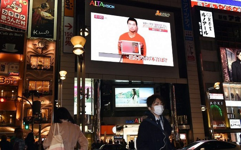 People look at a large TV screen in Tokyo on January 27, 2015 showing news reports about Japanese men Kenji Goto who has been kidnapped by the Islamic State group. (photo credit: Yoshikazu Tsuno/AFP)