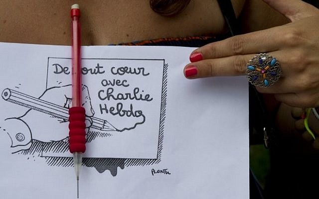 A woman holds a sign showing a cartoon by Plantu, outside the French Embassy in Buenos Aires on January 7, 2015, during a demonstration against the attack by gunmen in the offices of the satirical weekly Charlie Hebdo in Paris. (Photo credit: AFP/ALEJANDRO PAGNI)