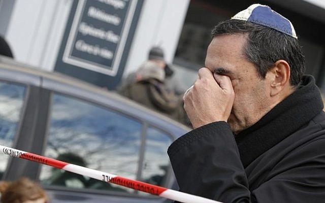 A man wearing a kippa cries near a kosher grocery store in Porte de Vincennes, in eastern Paris, on January 10, 2015, a day after four people were killed at the Jewish supermarket by jihadist gunman Amedy Coulibaly during a hostage-taking. (Photo credit: AFP/ KENZO TRIBOUILLARD)