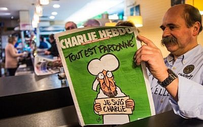 A man reads the latest edition of French satirical weekly Charlie Hebdo at a cafe in Dunkirk on January 14, 2015 shortly after the edition went on sale (photo credit: AFP/PHILIPPE HUGUEN) 