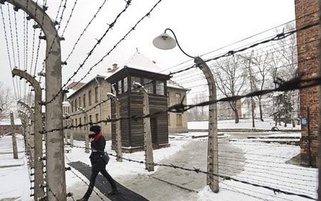 A visitor walks by barbed wire fences at the Auschwitz Nazi death camp in Oswiecim, Poland, Monday, Jan. 26, 2015. (AP/Alik Keplicz)