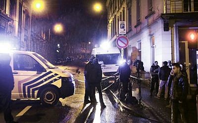Journalists and local residents stand near police vehicles as police set a large security perimeter in the city center of Verviers on January 15, 2015, during a "jihadist-related" anti-terrorism operation. (Photo credit: AFP/ BRUNO FAHY)