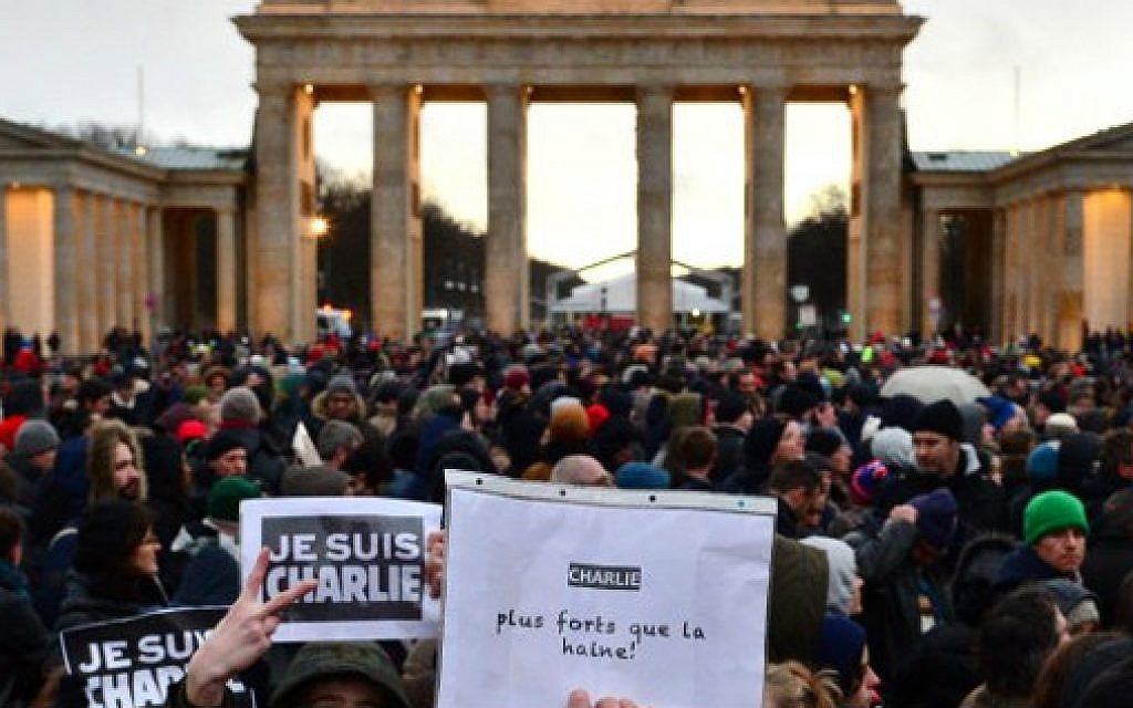 People hold up posters reading 'Je suis Charlie' (I am Charlie) and 'Charlie - plus forts que la haine' (Charlie - stronger than hate) during a rally in tribute to the 17 people killed in the terror attacks in France and in support of press freedom, in front of the Brandenburg Gate in Berlin on January 11, (photo credit: AFP/JOHN MACDOUGALL)