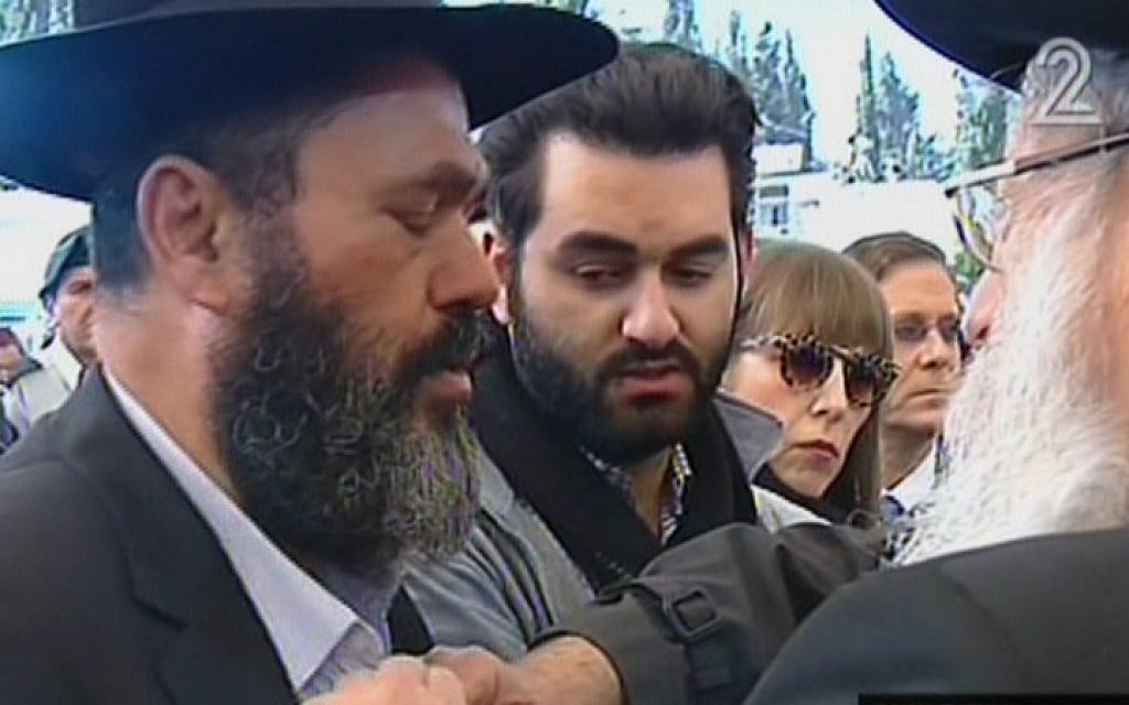 Rabbi Benjamin Hattab, the father of Yoav Hattab, who was killed in the Pairs kosher supermarket atack, rips his shirt in a Jewish sign of mourning during the funeral for his son and three other men killed in the attack, Tuesday, January 13, 2015 (screen capture: Channel 2)