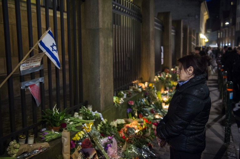 Well wishers reacts as they bring flowers and light candles to honor the shooting victims outside the main Synagogue in Copenhagen, Denmark on February 15, 2015 (photo credit: AFP/Odd Andersen)