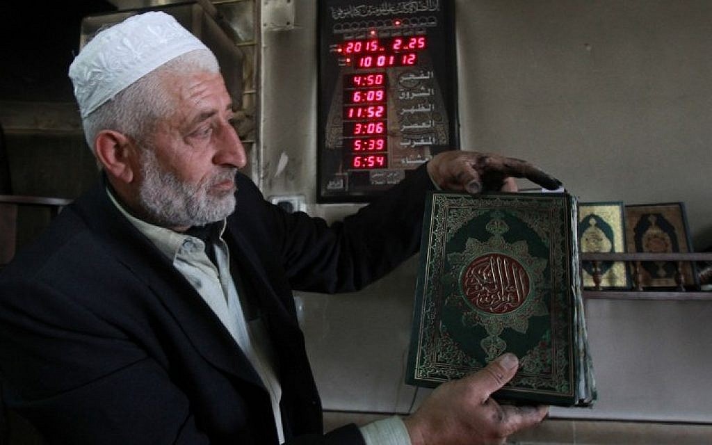 Palestinian Imam Ibrahim Abu Luha shows a burnt Koran, Islam's holy book, after a mosque was torched overnight in the West Bank village of al-Jaba, southwest of Bethlehem, February 25, 2015 .(photo credit: AFP/MUSA AL-SHAER)