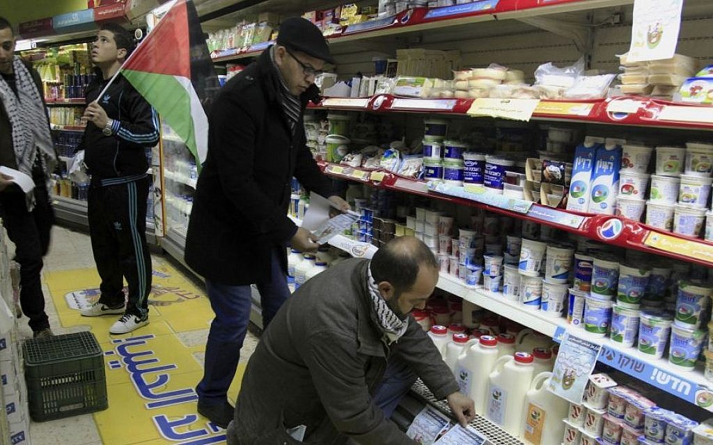 Illustrative: A Palestinian activist places a sign to boycott Israeli products at a supermarket in Bethlehem, West Bank,  February 11, 2015 (Mahmoud Illean/AP)