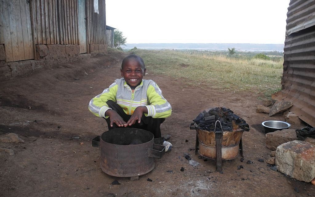 Njogu‘s son Moshe warms his hands over the fire. The high altitude and wind make this one of the colder parts of the country. (Melanie Lidman/Times of Israel)