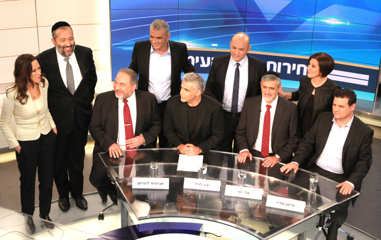 Foreign Minister and Yisrael Beytenu Chairman Avigdor Liberman (bottom L), Yair Lapid, leader of 'Yesh Atid' Party( bottom 2L), Leader of the Yachad party, Eli Yishai (bottom 2R), Leader of the combined Arab list, Ayman Odeh (bottom R), Meretz party leader Zahava Gal On (upper R), Leader of the ultra orthodox Shas party, Aryeh Deri (upper 2L), Leader of Habayit Hayehudi (Jewish Home) party, Naftali Bennett (upper 2R) and Leader of the Kulanu party Moshe Kahlon (upper C) and Channel 2 TV news anchorman, Yonit Levi (upper L) seen before a Channel 2 news political debate ahead of the 2015 Israeli election. in the Neve Ilan studios near Jerusalem on February 26, 2015. (Photo cedit: Channel 2 News)