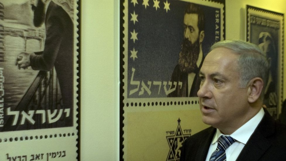 In this April 18, 2010 file photo, Prime Minister Benjamin Netanyahu looks at posters of stamps carrying the portrait of Theodor Herzl, the founder of modern Zionism, in Jerusalem. (Photo credit: AP/Sebastian Scheiner)