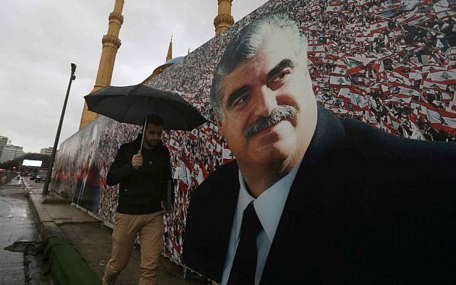 A Lebanese man walks by a giant poster of slain former Lebanese Prime Minister Rafik Hariri, that was put up near his grave, in preparation to mark the 10th anniversary of his assassination, in downtown Beirut, Lebanon, Wednesday, Feb. 11, 2015. (AP Photo/Hussein Malla)