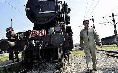 A Hellenic Railway officer walks in front of a train that was used by the Nazis to carry Jews from Thessaloniki to Auschwitz during the WWII, in the Greek northern town of Thessaloniki, on Sunday, March 15, 2015 (AP Photo/Giannis Papanikos)