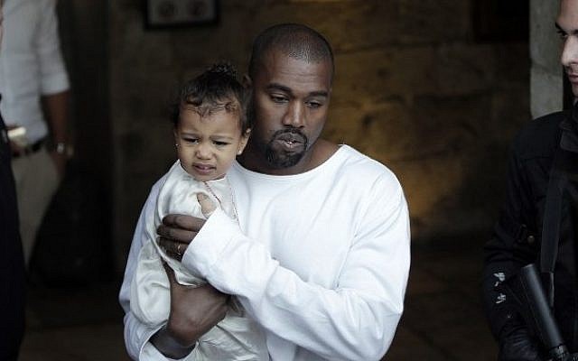 US rapper Kanye West, husband of US reality TV star Kim Kardashian, carries their daughter, North, following a reported baptism ceremony at the Armenian St. James Cathedral in Jerusalem's Old City on April 13, 2015. (photo credit: AFP/Ahmad Gharabli)