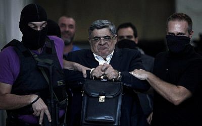 A file picture taken on September 28, 2013 shows the leader of ultra-right wing Golden Dawn party Nikos Michaloliakos being escorted by masked police officers to the prosecutor from the police headquarters in Athens, Greece. (AFP photo/Angelos Tzortzinis)