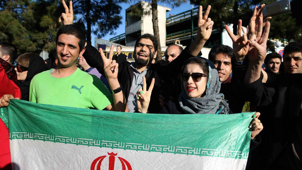 Iranians flash the victory sign as they hold their country's flag while waiting for arrival of Foreign Minister Mohammad Javad Zarif from Lausanne, Switzerland, at the Mehrabad airport in Tehran, Iran, Friday, April 3, 2015. (photo credit: AP/Ebrahim Noroozi)