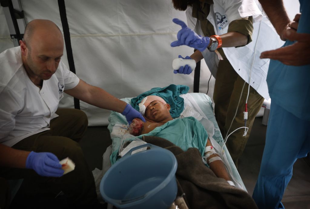 An Israeli doctor treats the wound of an earthquake-affected Nepalese boy, whose arm was amputated in the nearby army hospital and shifted for further treatment to the newly opened Israeli field hospital for earthquake victims in Kathmandu, Nepal, Wednesday, April 29, 2015. (Photo credit: AP/Manish Swarup)