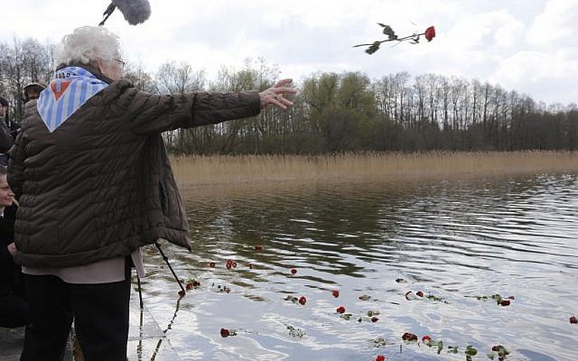 A camp survivor throws a rose into the lake during ceremonies at the former Nazi concentration camp Ravensbrück in northeastern Germany, Sunday, April 19, 2015, to commemorate the 70th anniversary of the liberation of the camp by the Red Army on April 30, 1945. (AP Photo/Ferdinand Ostrop)