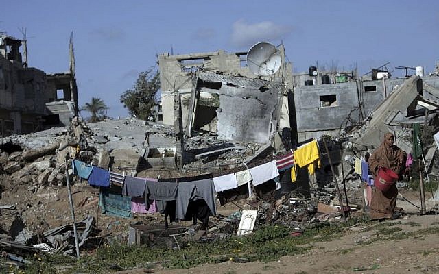 A Palestinian woman hangs washing next to the rubble of her destroyed house, in the Shijaiyah neighborhood of Gaza City, Monday, March 30, 2015.  (AP/Khalil Hamra)