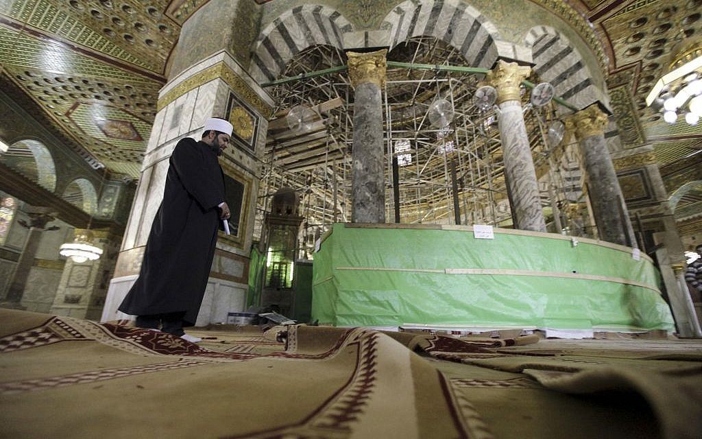 In this Sunday, April 19, 2015 photo, a cleric walks on the new carpets at the Dome of the Rock shrine in Jerusalem. (photo credit: AP/Mahmoud Illean)