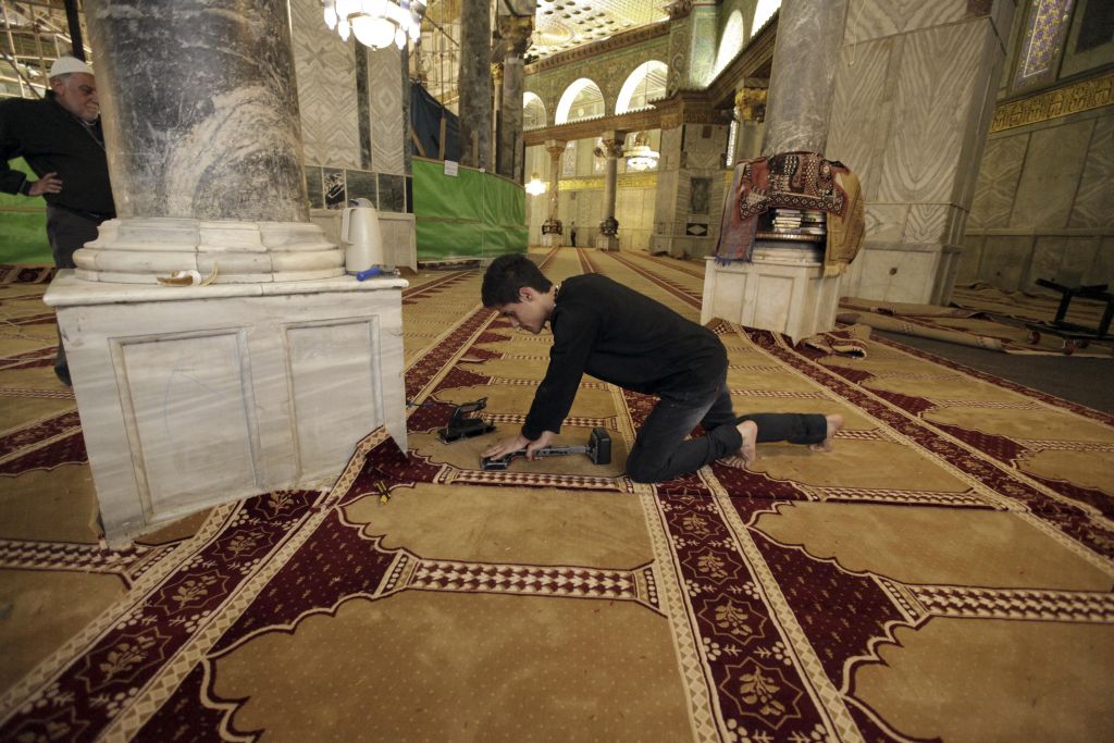 In this Sunday, April 19, 2015 photo, a worker places new carpets at the Dome of the Rock shrine in Jerusalem. (photo credit: AP Photo/Mahmoud Illean)