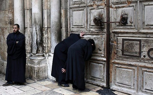 Christian Orthodox priests look through a hole in the main door of the Church of the Holy Sepulcher, before the Holy Fire ceremony around Jesus's tomb, in Jerusalem’s Old City, on April 11, 2015. (AFP/Thomas Coex)