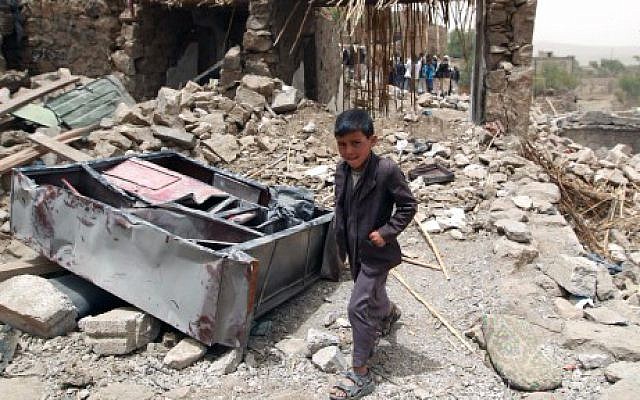 A Yemeni boy walks past the rubble of destroyed houses in the village of Bani Matar, 70 kilometers (43 miles) West of Sanaa, on April 4, 2015, a day after it was reportedly hit by an airstrike by the Saudi-led coalition against Shiite Houthi rebel positions. (photo credit: AFP/Mohammed Huwais)