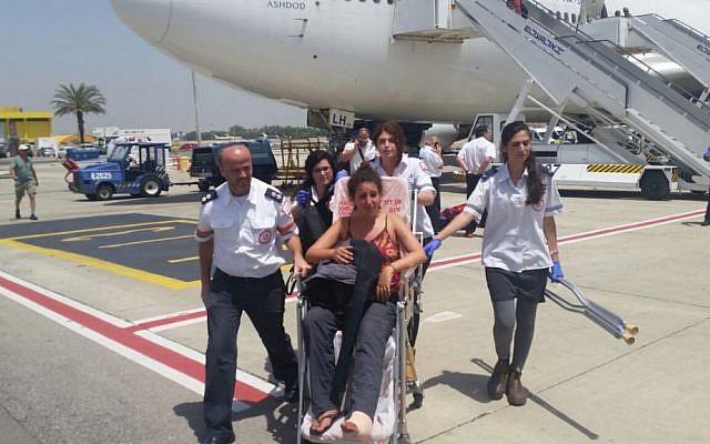 Magen David Adom medics escort an Israeli woman who flew to Israel in an emergency flight from Nepal following the earthquake there, at Ben Gurion Airport on Tuesday, April 28, 2015 (photo credit: MDA)