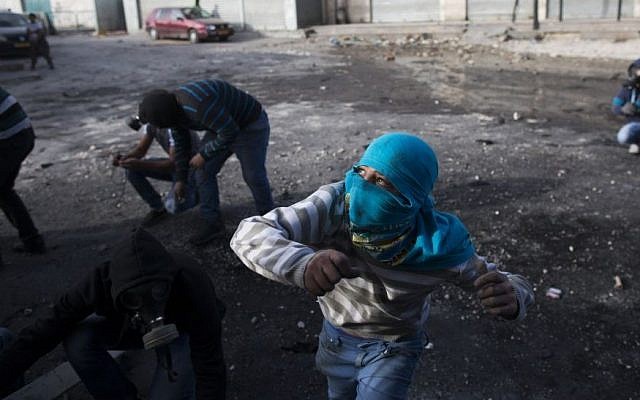 Palestinian youth throw stones during clashes with Border Police in the Shuafat refugee camp in Jerusalem following Friday prayers on November 7, 2014. (Yonatan Sindel/Flash90)