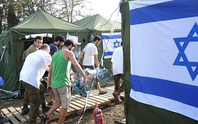 Israeli soldiers and doctors bring in an earthquake victim who arrived by jeep on Friday afternoon, May 1, 2015 (Photo credit: Melanie Lidman)